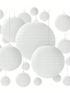 white paper lanterns hanging from strings in the shape of balls, with one light on each side