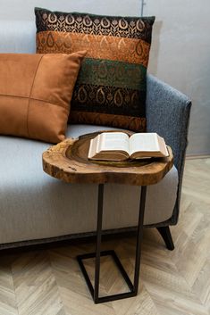 an open book sitting on top of a wooden table next to a couch with pillows