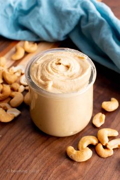 a jar filled with cashews sitting on top of a wooden table next to a blue towel