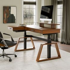 a computer desk with a monitor and keyboard on it in front of a large window