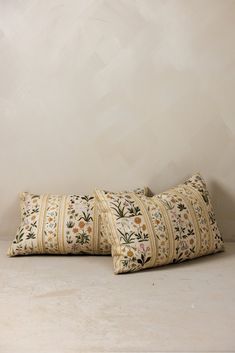 two pillows sitting on top of each other in front of a wall