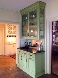 a kitchen with green cabinetry and black counter tops in the middle of the room