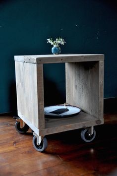 a wooden table with wheels and a vase on top