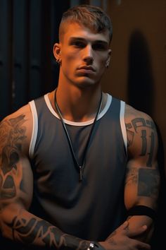 a young man with tattoos on his arms and chest posing for a photo in a dark room