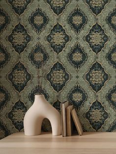 two vases sitting on top of a wooden table next to books and a wall paper