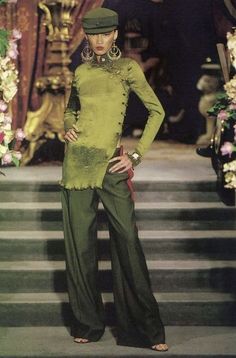 a woman in green is standing on the runway