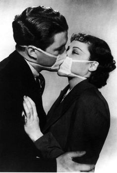 a man and woman kissing each other wearing masks