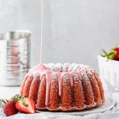 a bundt cake with icing drizzled over it and strawberries on the side