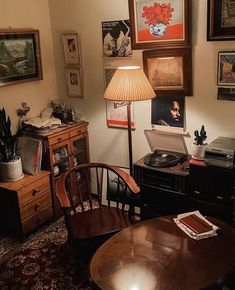 a living room filled with furniture and pictures on the wall next to a table topped with a record player