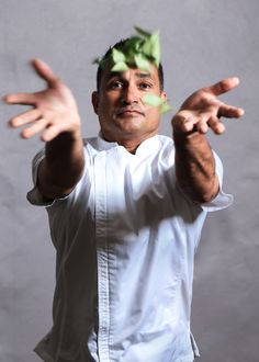 a man in a chef's uniform is throwing leaves into the air