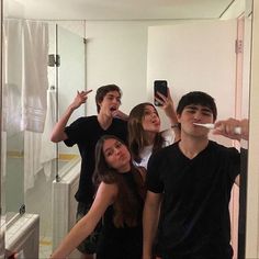 four people are taking a selfie in the bathroom while brushing their teeth with an electric toothbrush