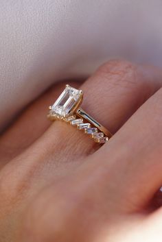 a woman's hand with a diamond ring on top of her finger and an engagement band