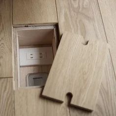 an open wooden box on the floor with some electrical plugs in it