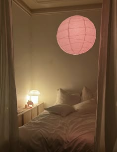 a bed sitting under a pink light in a bedroom