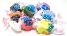 several different colored candies in wrappers on a white surface