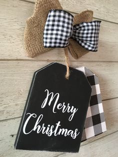 a black and white christmas sign hanging on the side of a wooden wall next to two burlocks