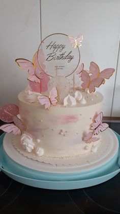 a white cake with pink butterflies on it and a happy birthday sign in the middle