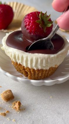 a person is cutting into a dessert on a paper plate with strawberries in the background