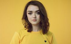 a woman in a yellow t - shirt poses for a photo against a yellow background