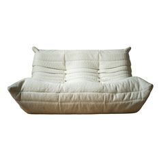 a white futon sofa with pillows on it's back and arms, in front of a white background