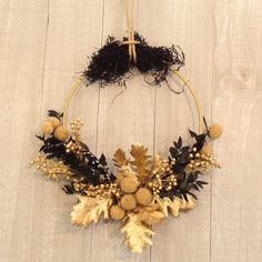 a wreath made out of dried flowers and leaves on a white wooden background with twine