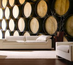 a living room filled with furniture and lots of wine barrels on the wall behind it