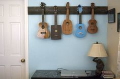 there are guitars hanging on the wall next to a table with a lamp in front of it