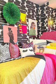 a bedroom with black and white wallpaper, colorful bedding and pictures on the walls