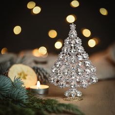 a small crystal christmas tree sitting on top of a table next to a lit candle