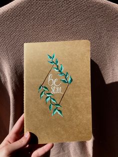 a person holding up a brown book with green leaves and the words be sure on it