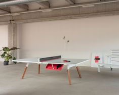 a ping pong table in an empty room next to a bench and potted plant