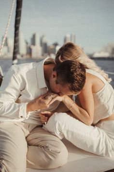 a man and woman kissing on the back of a boat