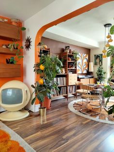 a living room filled with lots of furniture and plants on top of hard wood flooring