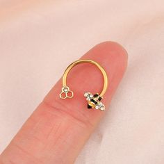 a person's finger with a gold nose ring and two small white stones on it