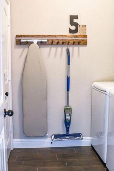 a white toilet sitting next to a dryer on top of a wooden shelf in a bathroom