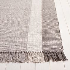 an area rug on the floor with white and gray stripes, including one fringed edge