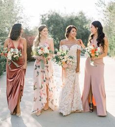 four bridesmaids are standing together and smiling at each other while holding bouquets