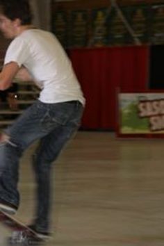 a man riding a skateboard on top of a hard wood floor