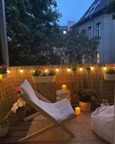 a small balcony with potted plants and lights on the wall, along with a white lawn chair