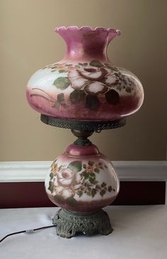 a pink and white vase sitting on top of a table next to a light bulb