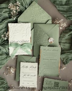 the wedding stationery is laid out on top of each other, including green and white paper