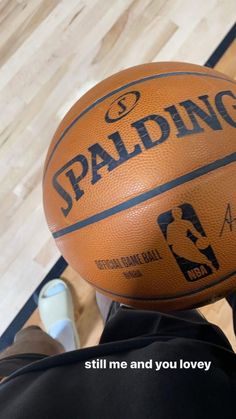 a basketball sitting on top of a wooden floor next to a person's feet