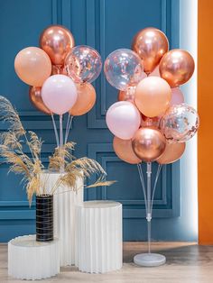 two vases filled with balloons on top of a wooden floor next to a blue wall