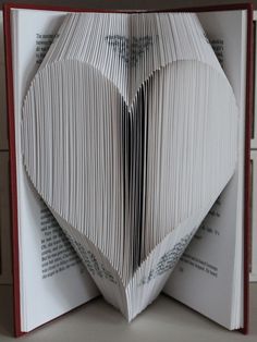 an open book with folded pages in the shape of a heart