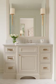 a white bathroom vanity with two sinks and large mirror above it, along with gold accents