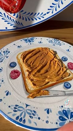 a piece of toast with peanut butter on it sitting on a blue and white plate