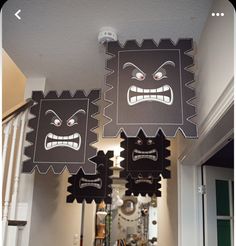 two black and white monster masks hanging from the ceiling in front of a staircase way