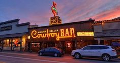 cars parked on the street in front of a building with neon lights and a sign that says las alam county