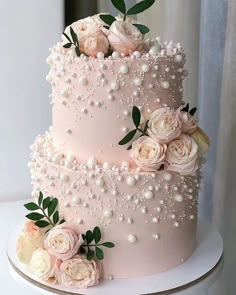 a pink wedding cake with white flowers and pearls