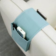 an electronic device is in the back pocket of a white chair with light blue fabric